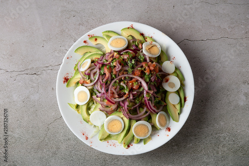 Fresh avocado salad topped with boiled eggs and red onion