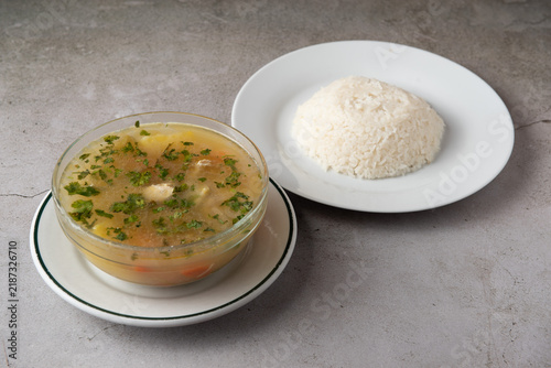 Homemade chicken soup with cilantro served alongside white rice