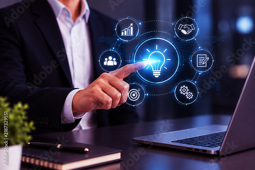 Businessman interacting with a digital interface of business icons and a glowing lightbulb