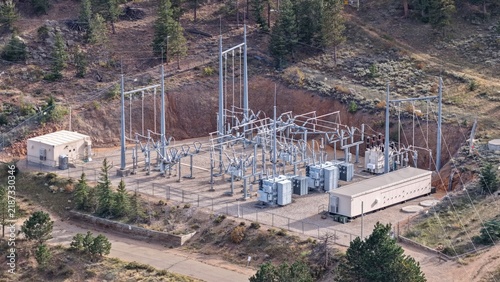 Aerial view of an electrical substation with transformers and power lines situated in a forested mountain area in Estes Park, Colorado, United States.