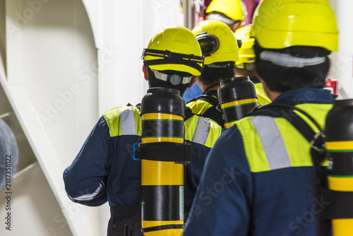 Obraz na płótnie Commercial vessel crew preparing for an emergency response exercise, with several seafarers equipped with SCBA sets and compressed-air bottles