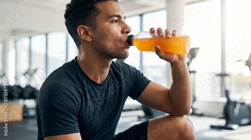 Athletic Man Drinking Hydrating Sports Drink from Plastic Bottle in Bright Setting - Fitness and Beverage Commercial Stock Photo