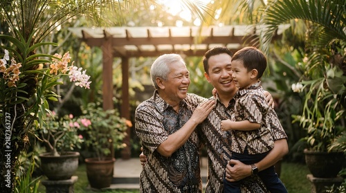 Three generations of Asian men posing together in a lush garden.