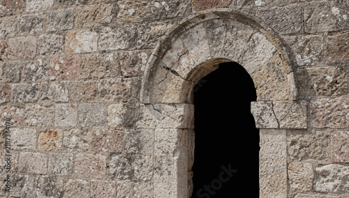an old arched stone doorway embedded in a rustic masonry wall