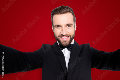 Obraz na płótnie Self portrait of stylish cheerful artist in black suit with bowtie, shooting sel