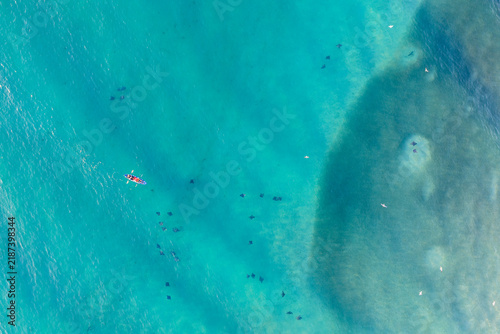 Aerial view of a kayak paddling over a large school of stingrays in the clear turquoise waters of Cape Byron, Byron Bay, New South Wales, Australia.