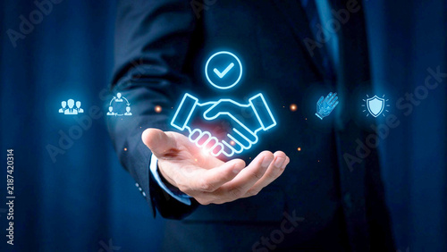 Business handshake icon glowing in a businessman hand for corporate agreement and partnership concept