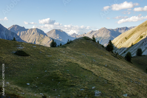 Bild auf Leinwand Paysage alpin avec randonneur sur colline les bras levés