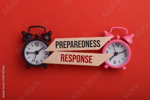 Obraz na płótnie Alarm clocks and wooden signs labeled Preparedness and Response, symbolizing emergency planning, readiness, crisis management, and timely action