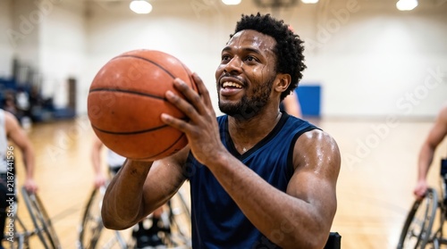 Focused wheelchair basketball player dribbling with determination in gym setting