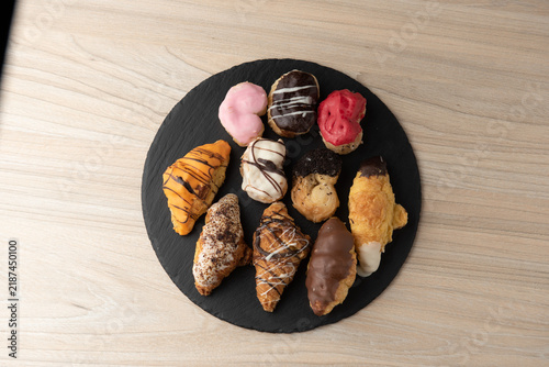 Assorted glazed mini palmier pastries and croissants on round slate tray