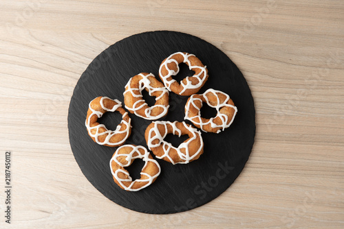 Artisanal fried glazed donuts on round black slate plate