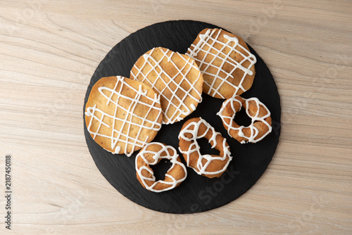 Assorted iced biscuits and traditional donuts on round slate plate