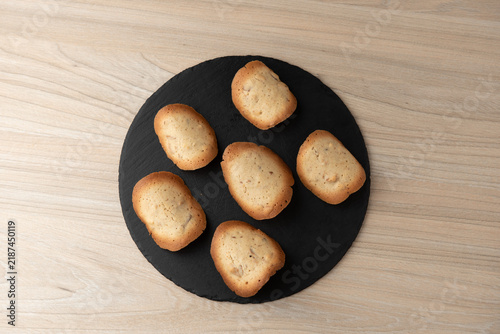 Artisanal almond tile cookies on round black slate tray