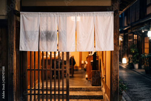 Naklejka 夜の和食店の入口に掛かる白い暖簾と温かな灯り