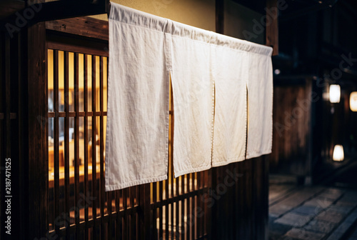 Naklejka 夜の和食店の入口に掛かる白い暖簾と温かな灯り