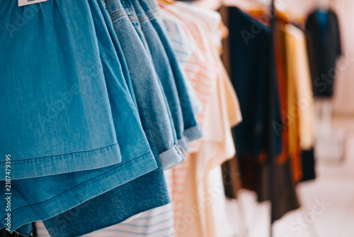Cuadro en lienzo A variety of clothing items, including skirts and shirts, hang on display racks inside a retail store
