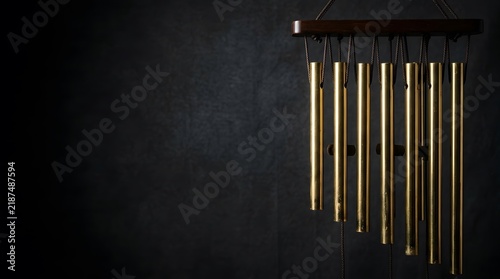 A close up of a wind chime against a black wall.