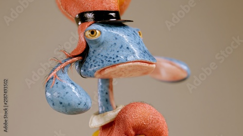 Whimsical blue toy dog character wearing an orange hat, creating a quirky playful portrait with surreal handmade aesthetics