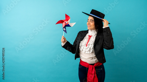 Canvas Print Young woman in traditional huasa costume holding a chilean flag pinwheel