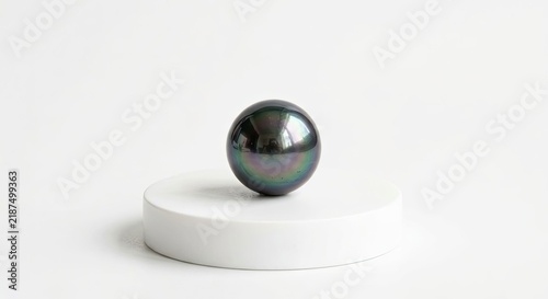 Single black pearl on white round pedestal.