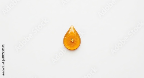 Single amber liquid drop on white.