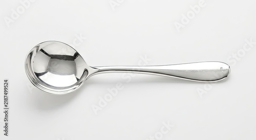 Small silver dessert spoon on white surface.