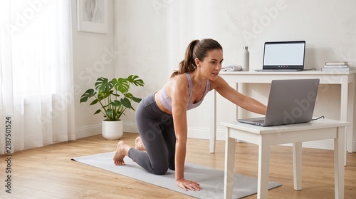 Young woman exercising during a virtual fitness class at home  