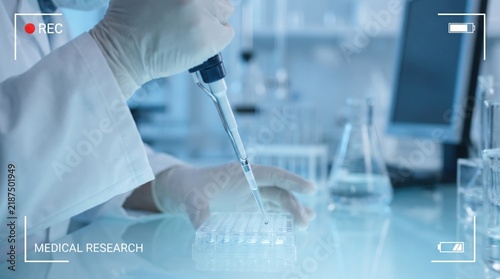 Scientist using a pipette to transfer liquid into a microplate in a modern laboratory setting with researcher wearing gloves uses micropipette dispense chemical sample multiwell plate laboratory coat