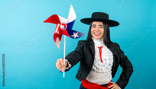 Obraz na plátně Happy woman wearing huaso attire, holding a chilean flag pinwheel