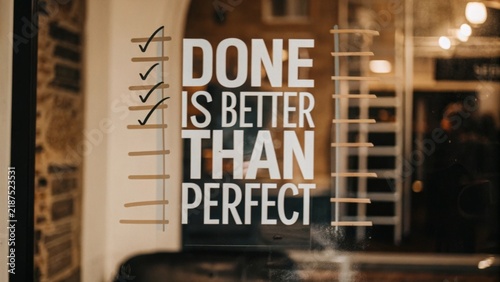 Inspiring message displayed on a glass door emphasizing that completing tasks is more valuable than striving for perfection to boost productivity and foster personal development