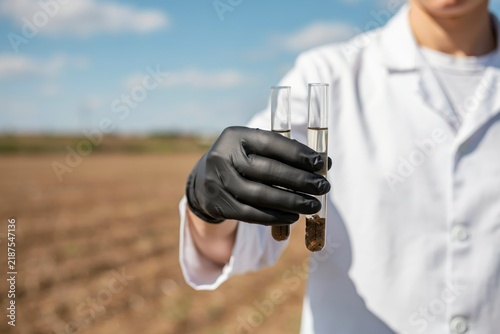Scientist holding test tubes with soil samples in a field
