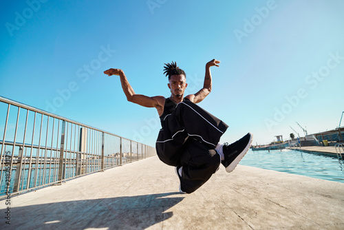 Foto Male breakdancer balancing on one leg by water
