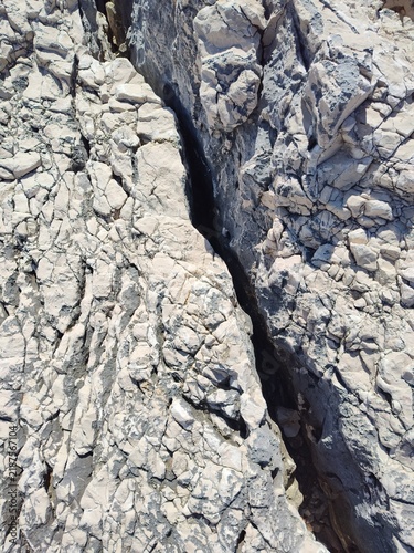 Natural stone wall texture featuring weathered rock patterns inspired by the ocean, beach, mountains, and the elements of the earth; limestone coast of the Adriatic Sea, island of Cres.