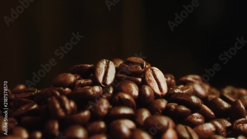 Pile of roasted coffee beans stock video footage close up. Stock video footage of a close up pile of roasted coffee beans on a dark moody background.