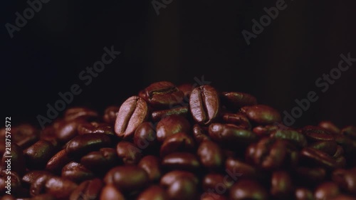 Pile of roasted coffee beans stock video footage close up on dark surface. Stock video footage of a close up pile of roasted coffee beans on a dark moody surface for food and drink concepts.