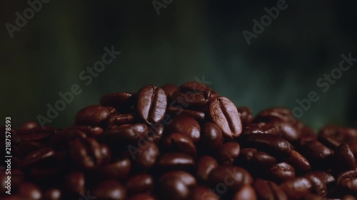 Pile of roasted coffee beans with smoke stock video footage macro. Stock video footage of a close up pile of roasted coffee beans with gentle smoke on a dark moody background.