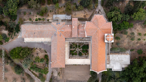 Latrun, Israel - 06 November 2025: Aerial view of Latrun Monastery, featuring its distinct terracotta-tiled roof, central courtyard with geometric garden patterns, and surrounding lush greenery.