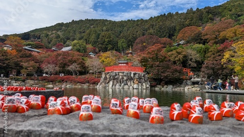 Konstfotografi Pequeños muñecos Daruma en primer plano con el estanque y el templo katsuo-ji ro
