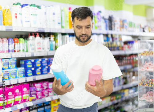 Quadro su tela Man examines product shampoo or shower gel while purchase in store