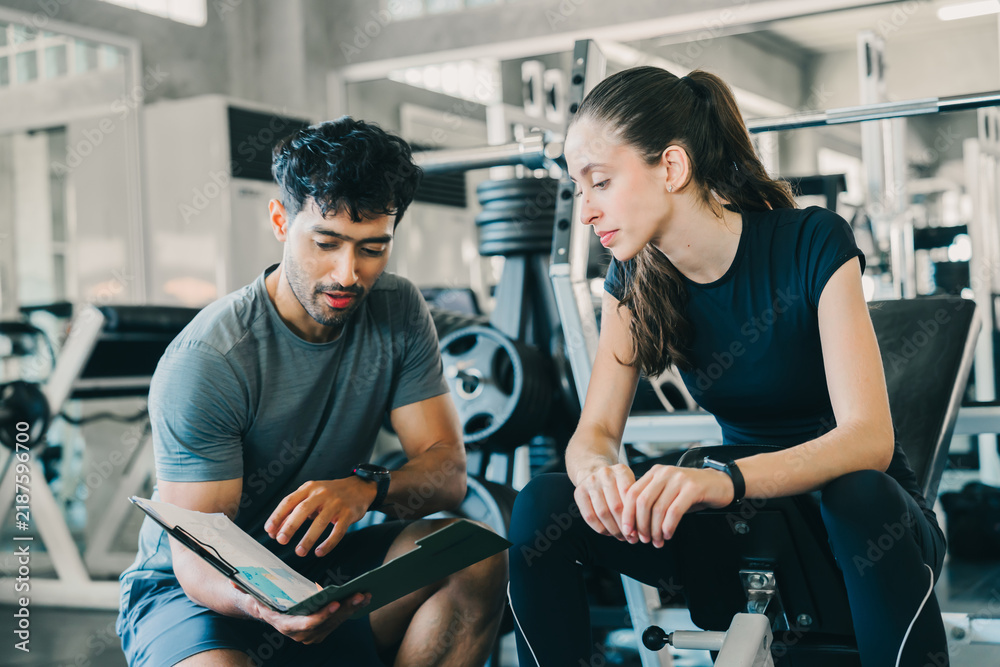 Fototapeta premium Professional personal trainer man and woman focused gym fitness exercising health care in gym during goal setting with happy emotion