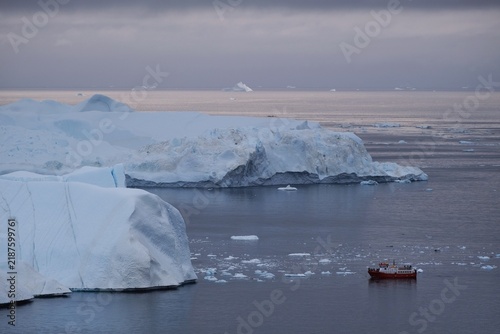 Motorboat sails near icebergs in Ilulissat,  Disko Bay, Greenland, Denmark.