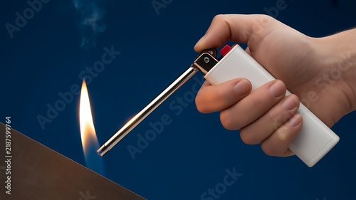 A Close-Up Photograph Of A Hand Using A Long Reach Utility Lighter To Ignite A Flame Against A Deep Blue Background