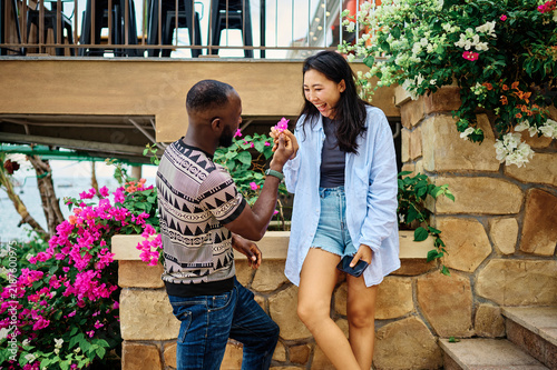Foto A laughing couple share a playful romantic moment by the seaside, surrounded by colorful bougainvillea and lush greenery