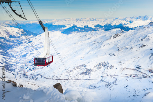 Gondola lift cabin in ski resort in winter Alps mountains, France. Snow-covered mountains and the blue sky at sunny day. Three valleys, Val Thorens, France