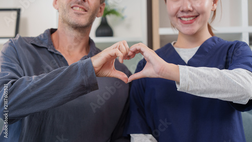 Quadro su tela Male patient and Asian healthcare worker making heart shape with hands for medic