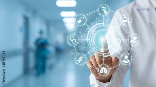 A male doctor in a white lab coat touching a futuristic glowing blue medical interface panel with icons in a blurred hospital hallway background.
