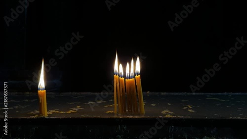 Burning religious candles in a church on a dark background, warm candlelight and spiritual atmosphere