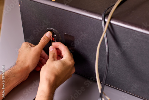 Quadro su tela Close-up of hands plugging audio cable into speaker jack with visible fingertip