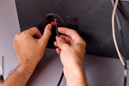 Fotografie Close-up of hands plugging audio cable into speaker jack with visible fingertip
